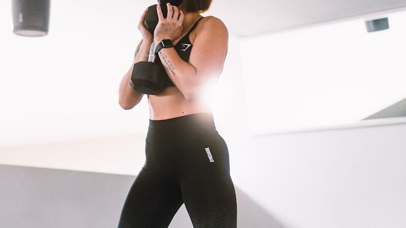 woman in black tank top and blue leggings doing yoga